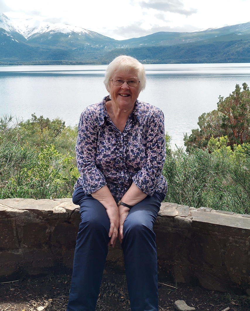 Joan smiling outdoors by a lake