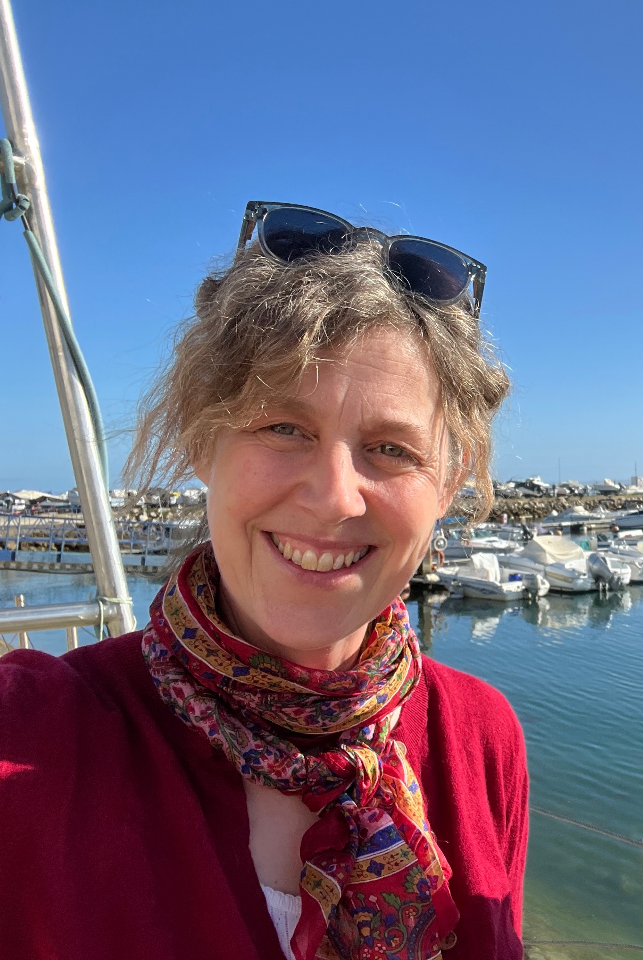 Mary smiling outdoors by the marina